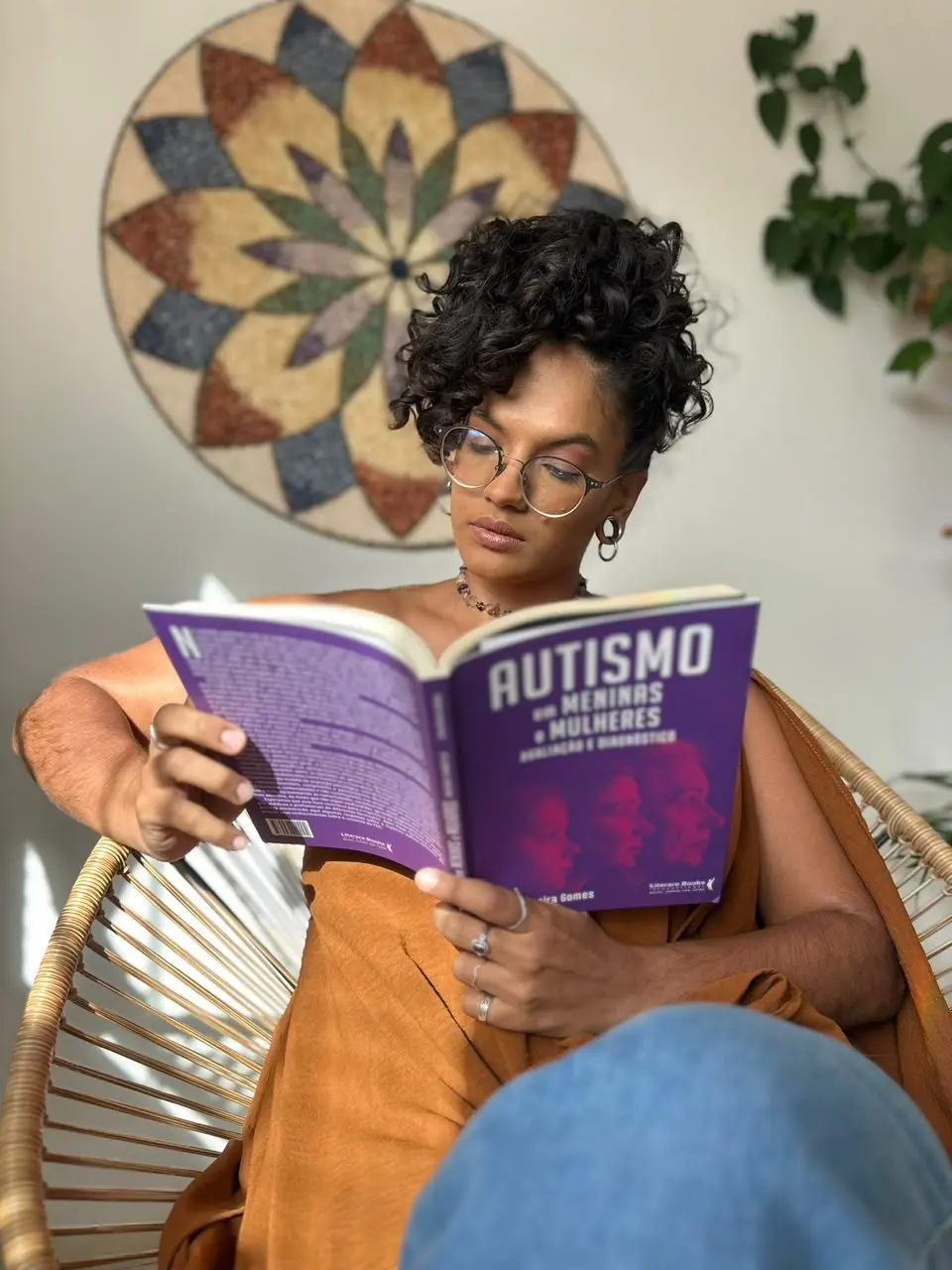Vitória lendo, sentada numa poltrona de fibra