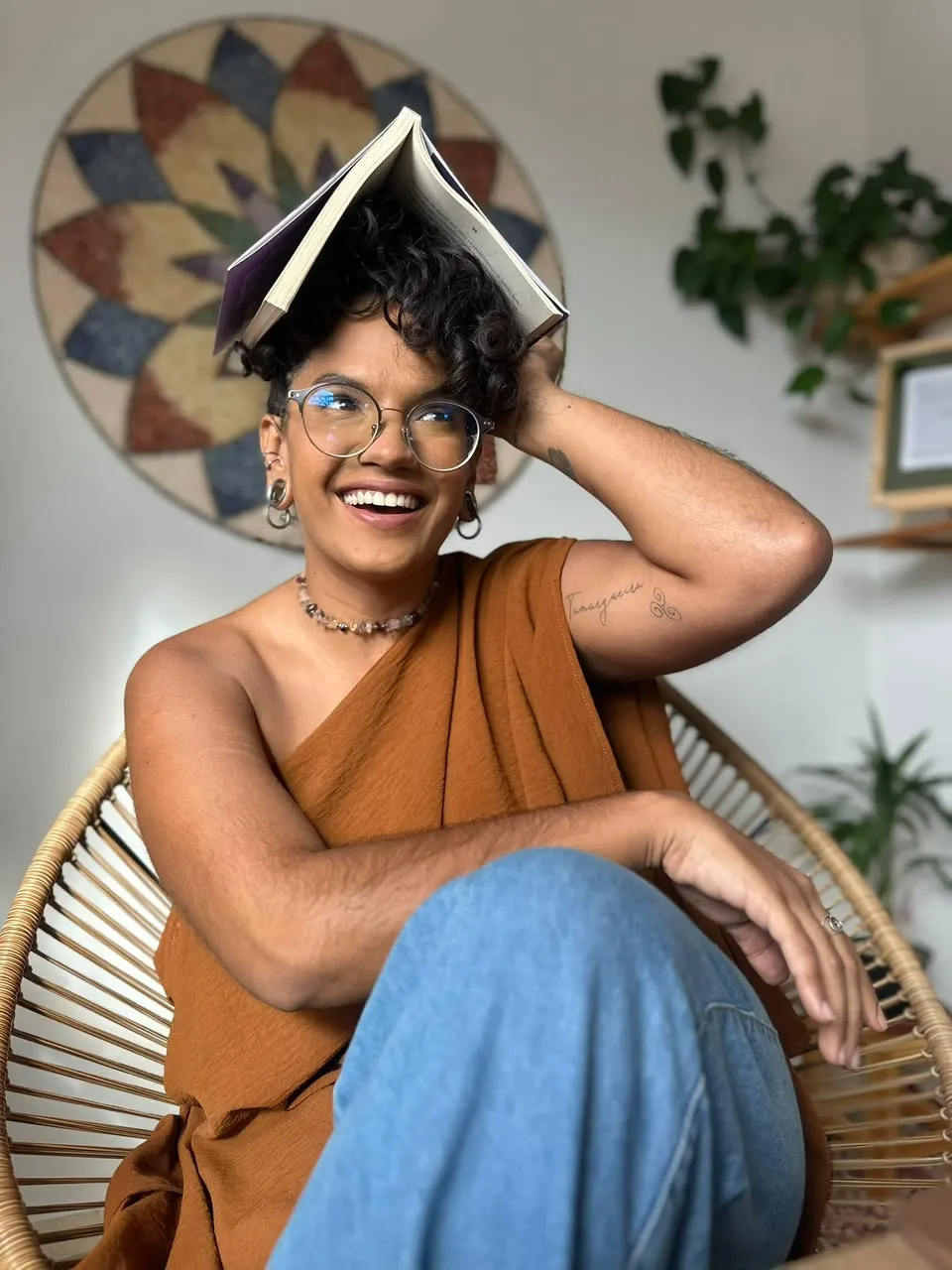 Vitória sorrindo com um livro aberto apoiado na cabeça